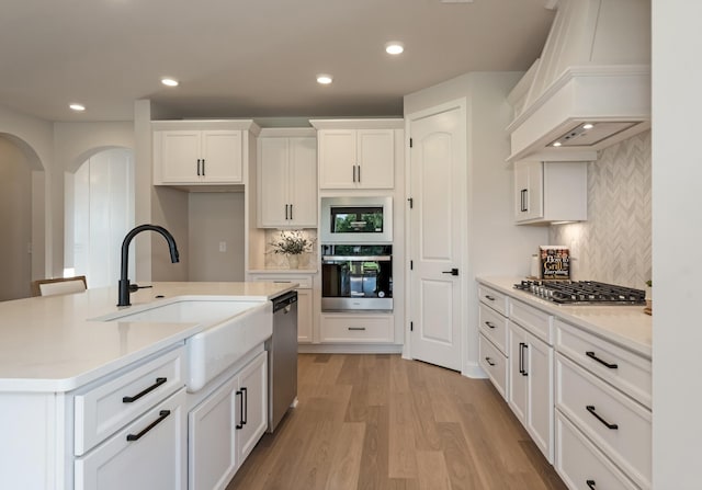 204 Phillips Bnd, Spring Hill, TN 37174 - kitchen featuring premium range hood, stainless steel appliances, arched walkways, decorative backsplash, and recessed lighting