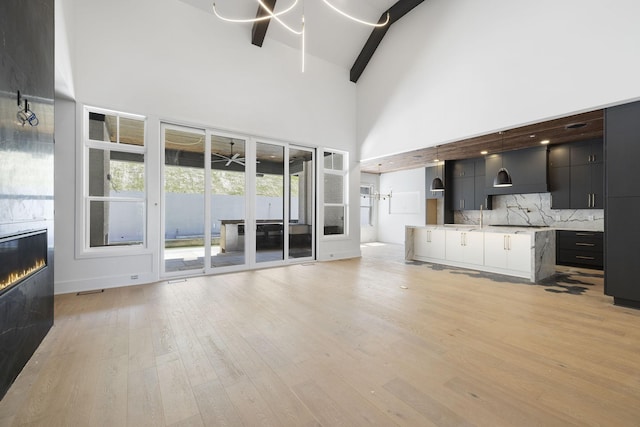 1884 Barnstaple Ln, Brentwood, TN 37027 - unfurnished living room featuring high vaulted ceiling, light wood-style flooring, beamed ceiling, and a tiled fireplace