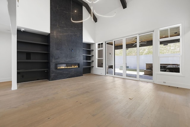 1884 Barnstaple Ln, Brentwood, TN 37027 - unfurnished living room featuring built in shelves, wood finished floors, a towering ceiling, and a fireplace