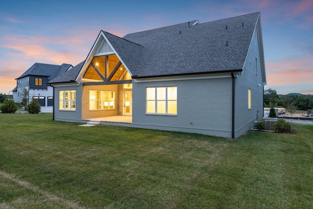 3244 Arundel Ln, Thompsons Station, TN 37179 - back of property at dusk featuring a shingled roof, a lawn, and brick siding