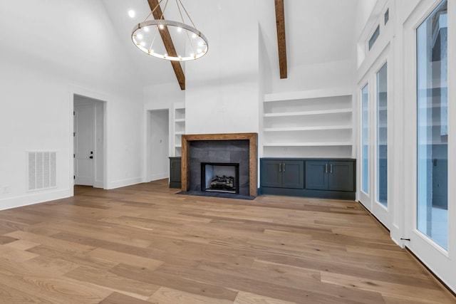 3244 Arundel Ln, Thompsons Station, TN 37179 - unfurnished living room featuring a chandelier, high vaulted ceiling, light wood-style flooring, beamed ceiling, and built in shelves