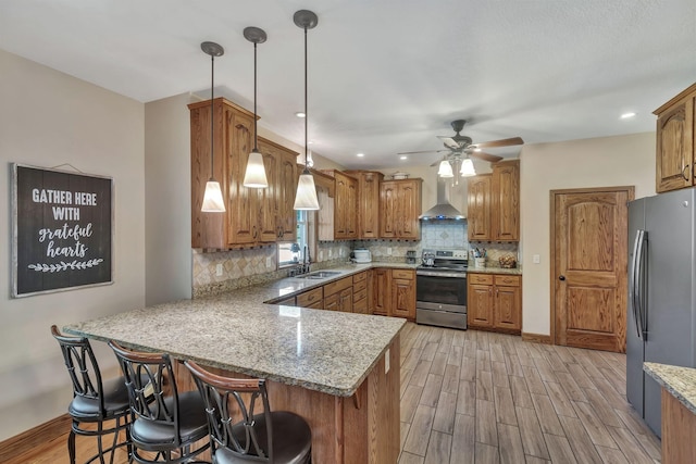 3534 Summertown Hwy, Summertown, TN 38483 - kitchen with stainless steel appliances, a peninsula, wall chimney range hood, brown cabinets, and light wood-style flooring