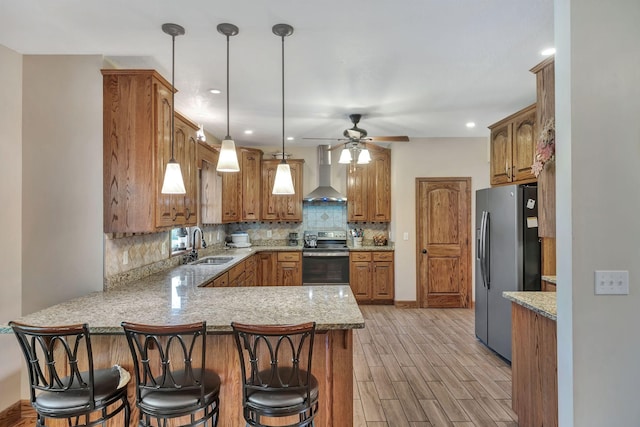 3534 Summertown Hwy, Summertown, TN 38483 - kitchen featuring appliances with stainless steel finishes, wall chimney range hood, a peninsula, light wood finished floors, and brown cabinetry