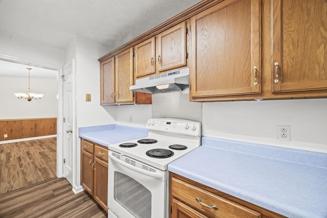 7125 Sutton Pl, Fairview, TN 37062 - kitchen with white electric range, under cabinet range hood, wood finished floors, a chandelier, and brown cabinets