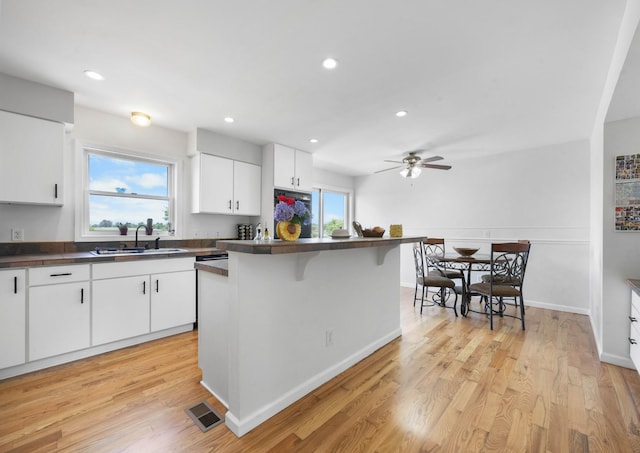 3899 Sadlersville Rd, Adams, TN 37010 - kitchen featuring dark countertops, white cabinetry, a breakfast bar, a ceiling fan, and light wood finished floors