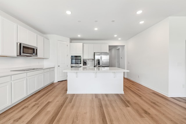 2337 Williamsport Lndg, Columbia, TN 38401 - kitchen featuring appliances with stainless steel finishes, light wood finished floors, recessed lighting, white cabinetry, and a kitchen island with sink