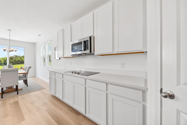 2337 Williamsport Lndg, Columbia, TN 38401 - kitchen with stainless steel microwave, light wood-type flooring, a chandelier, light countertops, and white cabinets