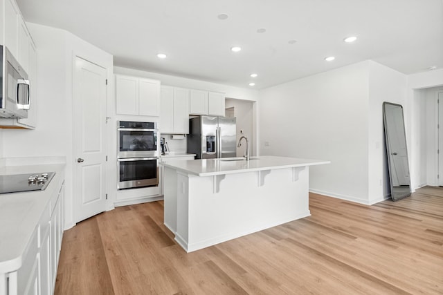 2337 Williamsport Lndg, Columbia, TN 38401 - kitchen featuring appliances with stainless steel finishes, light wood-style floors, a center island with sink, recessed lighting, and a breakfast bar area