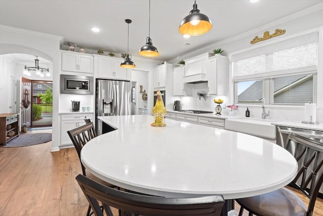 1055 Sumner Grv, Spring Hill, TN 37174 - kitchen with stainless steel appliances, custom range hood, arched walkways, ornamental molding, and light countertops
