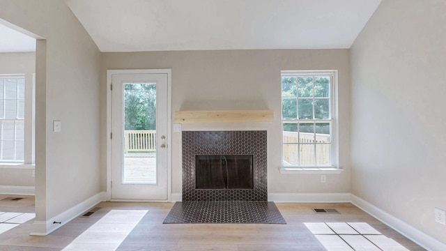 7313 Horn Tavern Ct, Fairview, TN 37062 - unfurnished living room featuring light wood-type flooring, vaulted ceiling, plenty of natural light, and a tiled fireplace