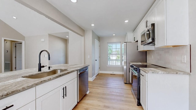 7313 Horn Tavern Ct, Fairview, TN 37062 - kitchen with appliances with stainless steel finishes, light stone countertops, light wood-style floors, white cabinets, and tasteful backsplash