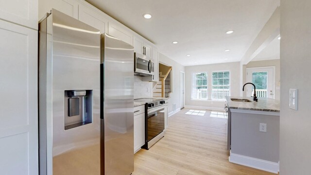 7313 Horn Tavern Ct, Fairview, TN 37062 - kitchen with stainless steel appliances, white cabinetry, light wood-type flooring, stone counters, and recessed lighting