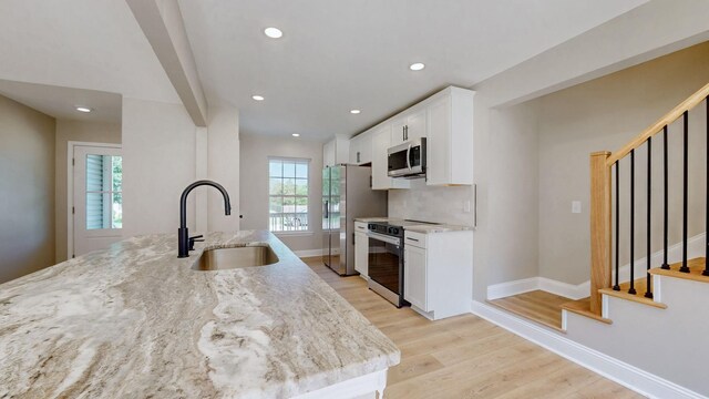 7313 Horn Tavern Ct, Fairview, TN 37062 - kitchen with appliances with stainless steel finishes, white cabinetry, light stone countertops, light wood-style floors, and recessed lighting