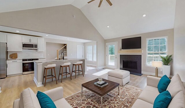 7313 Horn Tavern Ct, Fairview, TN 37062 - living room with high vaulted ceiling, light wood-style flooring, ceiling fan, healthy amount of natural light, and a tile fireplace