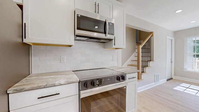 7313 Horn Tavern Ct, Fairview, TN 37062 - kitchen with appliances with stainless steel finishes, light wood finished floors, backsplash, white cabinets, and recessed lighting