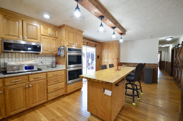 1355 Westfield Rd, Dickson, TN 37055 - kitchen with appliances with stainless steel finishes, a breakfast bar area, backsplash, a textured ceiling, and light wood-type flooring