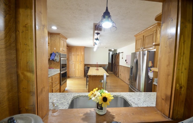 1355 Westfield Rd, Dickson, TN 37055 - kitchen featuring stainless steel appliances, light wood-style flooring, a textured ceiling, a kitchen island, and decorative light fixtures