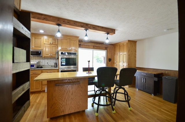 1355 Westfield Rd, Dickson, TN 37055 - kitchen with appliances with stainless steel finishes, wood walls, a center island, light wood-style flooring, and a wainscoted wall