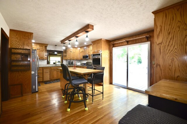 1355 Westfield Rd, Dickson, TN 37055 - kitchen featuring stainless steel appliances, brown cabinets, light wood-style flooring, decorative backsplash, and a center island