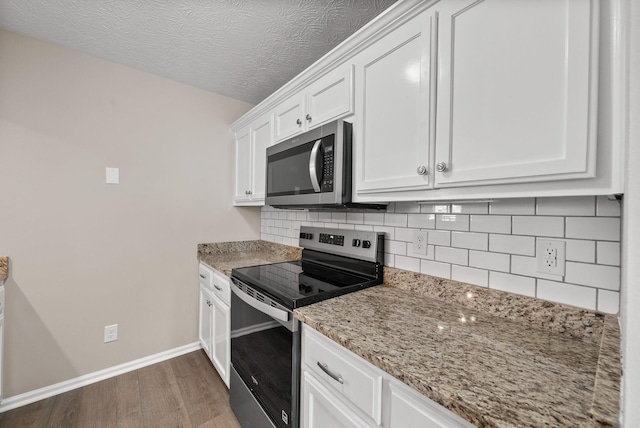 3798 Bret Dr, Clarksville, TN 37040 - kitchen with appliances with stainless steel finishes, wood finished floors, decorative backsplash, white cabinetry, and a textured ceiling