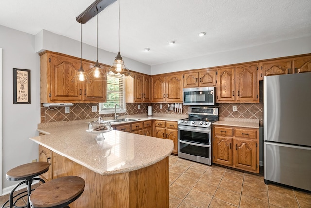 915 Rocky Hollow Rd, Erin, TN 37061 - kitchen featuring stainless steel appliances, a peninsula, brown cabinetry, tasteful backsplash, and hanging light fixtures