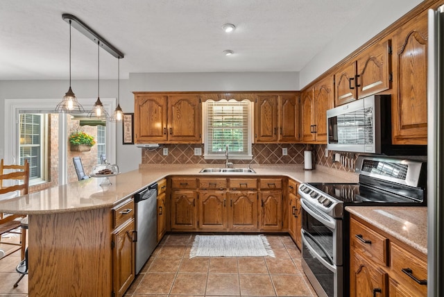 915 Rocky Hollow Rd, Erin, TN 37061 - kitchen featuring appliances with stainless steel finishes, a peninsula, brown cabinets, a breakfast bar, and tasteful backsplash