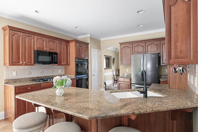 9732 Turnbridge Ct, Brentwood, TN 37027 - kitchen with black appliances, a peninsula, a breakfast bar, arched walkways, and light stone countertops