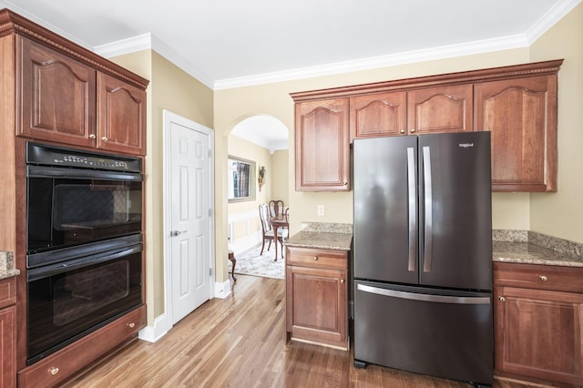 9732 Turnbridge Ct, Brentwood, TN 37027 - kitchen with freestanding refrigerator, ornamental molding, light wood-type flooring, arched walkways, and light stone countertops