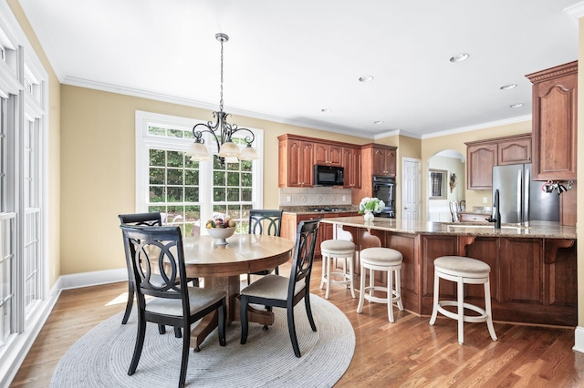 9732 Turnbridge Ct, Brentwood, TN 37027 - dining space featuring arched walkways, crown molding, light wood finished floors, a chandelier, and recessed lighting