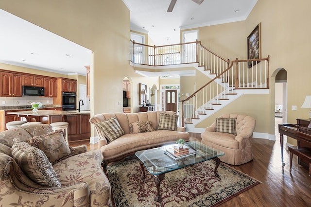 9732 Turnbridge Ct, Brentwood, TN 37027 - living area featuring arched walkways, wood finished floors, stairway, a towering ceiling, and ornamental molding