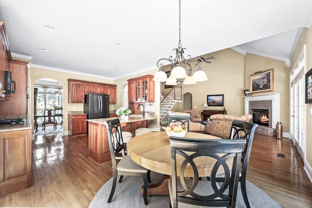 9732 Turnbridge Ct, Brentwood, TN 37027 - dining space with arched walkways, dark wood-style floors, a brick fireplace, a chandelier, and stairway