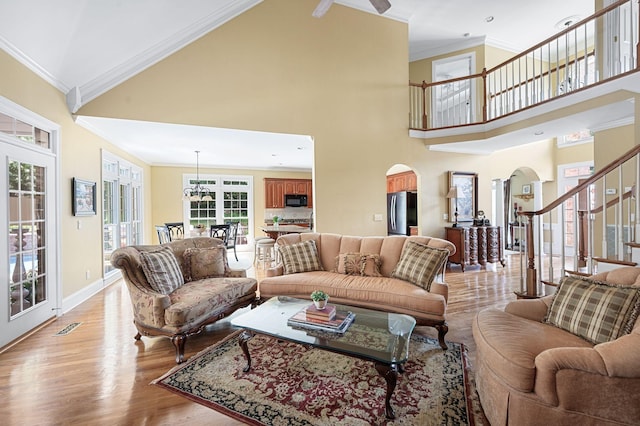 9732 Turnbridge Ct, Brentwood, TN 37027 - living area with arched walkways, crown molding, stairs, high vaulted ceiling, and light wood-style floors