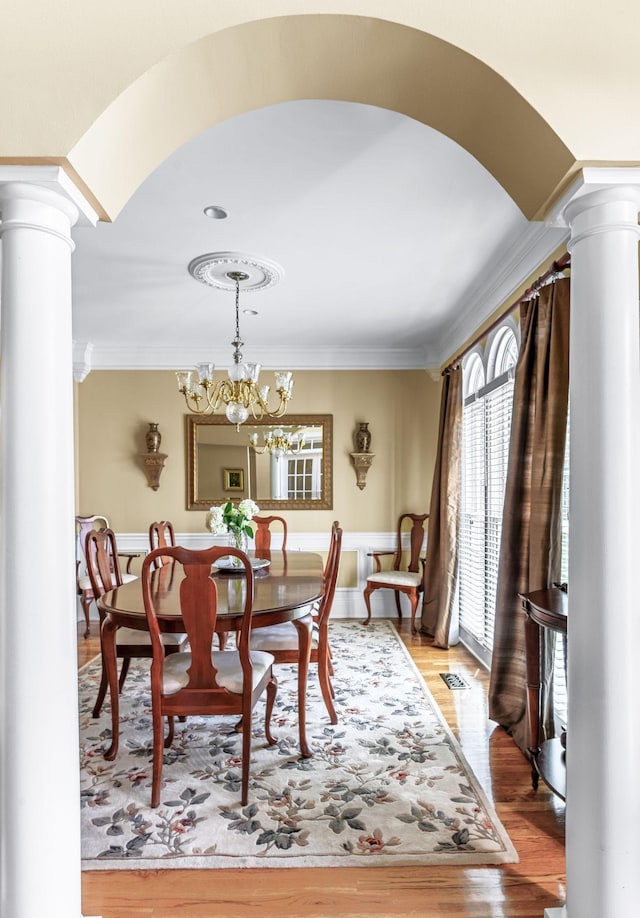 9732 Turnbridge Ct, Brentwood, TN 37027 - dining space featuring decorative columns, ornamental molding, arched walkways, light wood-style flooring, and a chandelier