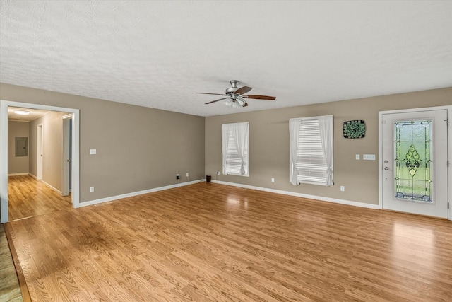 3135 Mullins Rd, Byrdstown, TN 38549 - unfurnished living room featuring light wood-type flooring, ceiling fan, electric panel, and a textured ceiling