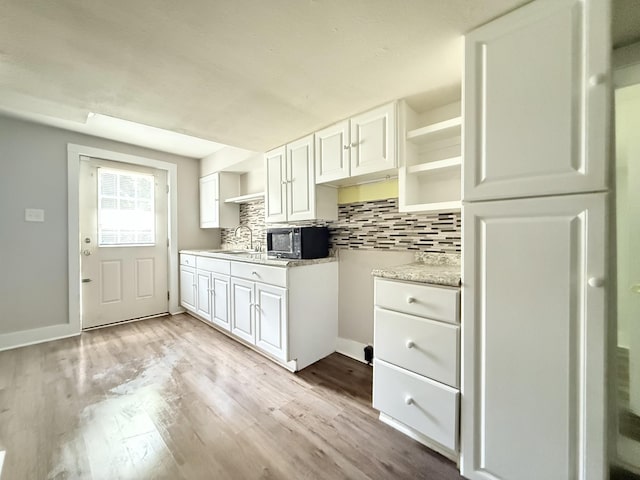2844 Jarman Hollow Rd, Palmyra, TN 37142 - kitchen with black microwave, open shelves, backsplash, and light wood-style flooring