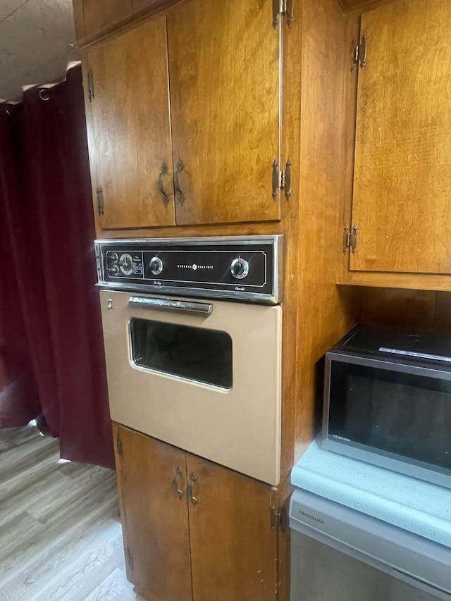 1212 Poplar Dr, Lawrenceburg, TN 38464 - kitchen with white oven, light wood-style floors, brown cabinets, and dishwasher
