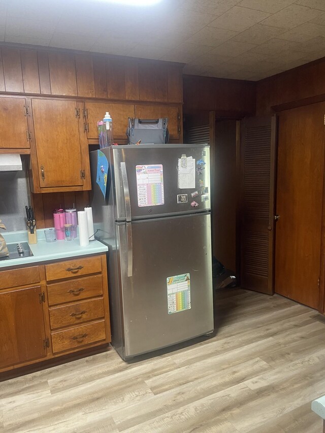 1212 Poplar Dr, Lawrenceburg, TN 38464 - kitchen with freestanding refrigerator, brown cabinetry, light wood-type flooring, and light countertops