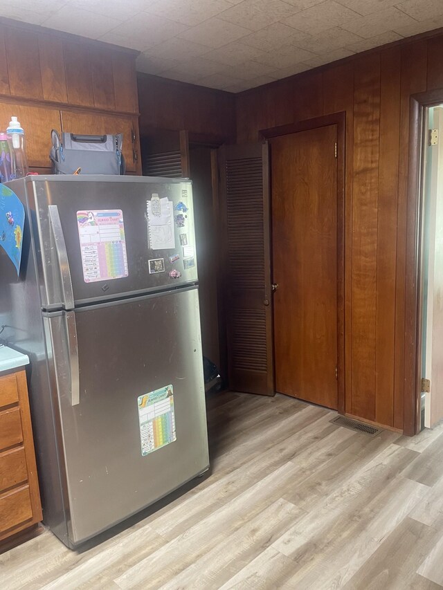 1212 Poplar Dr, Lawrenceburg, TN 38464 - kitchen featuring freestanding refrigerator, light wood-type flooring, brown cabinets, and wood walls