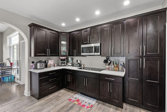 3723 Reed Rd, Indian Mound, TN 37079 - kitchen featuring stainless steel microwave, arched walkways, black electric stovetop, light countertops, and light wood-style flooring