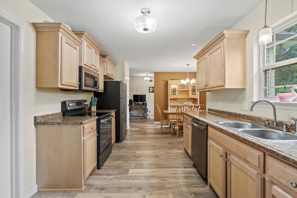 414 Grace St, Springfield, TN 37172 - kitchen featuring stainless steel appliances, light brown cabinetry, light wood-style flooring, a chandelier, and pendant lighting