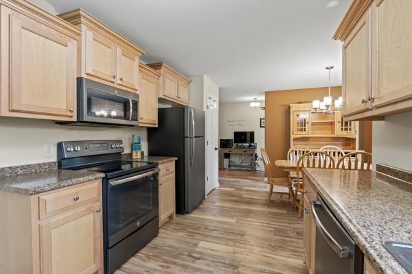 414 Grace St, Springfield, TN 37172 - kitchen with appliances with stainless steel finishes, light brown cabinetry, light wood finished floors, a chandelier, and stone countertops