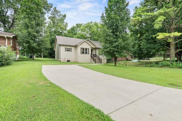414 Grace St, Springfield, TN 37172 - view of front facade featuring a front lawn, concrete driveway, and view of wooded area