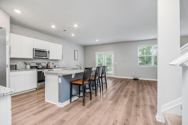 124 Nunally Dr, Baxter, TN 38544 - kitchen with stainless steel appliances, light wood-style floors, white cabinets, a kitchen island with sink, and recessed lighting