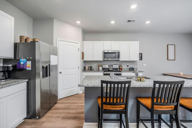 124 Nunally Dr, Baxter, TN 38544 - kitchen featuring appliances with stainless steel finishes, a kitchen bar, white cabinetry, light wood-type flooring, and a center island with sink