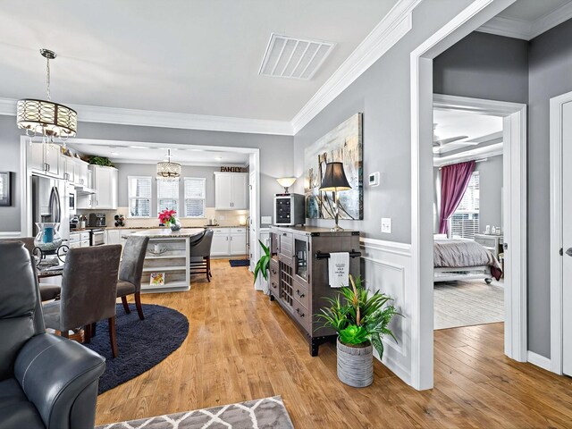 141 Tipton Pass, Spring Hill, TN 37174 - living area featuring light wood-style floors, healthy amount of natural light, ornamental molding, a chandelier, and wainscoting