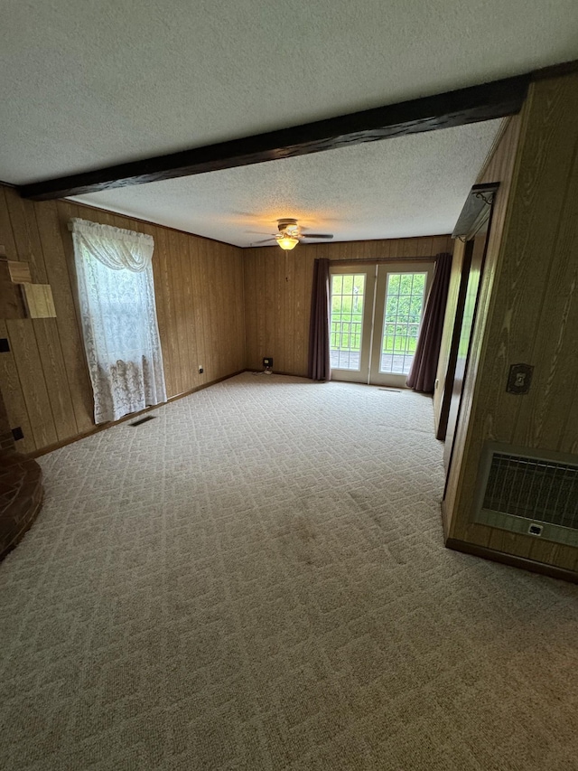3911 Old Bottom Rd, Lafayette, TN 37083 - unfurnished living room with a textured ceiling, wood walls, carpet, beamed ceiling, and a ceiling fan