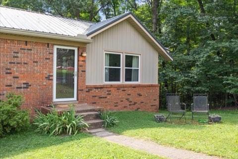 101 Cedar Hill Dr, Waverly, TN 37185 - view of front of property featuring brick siding, a front yard, and a metal roof