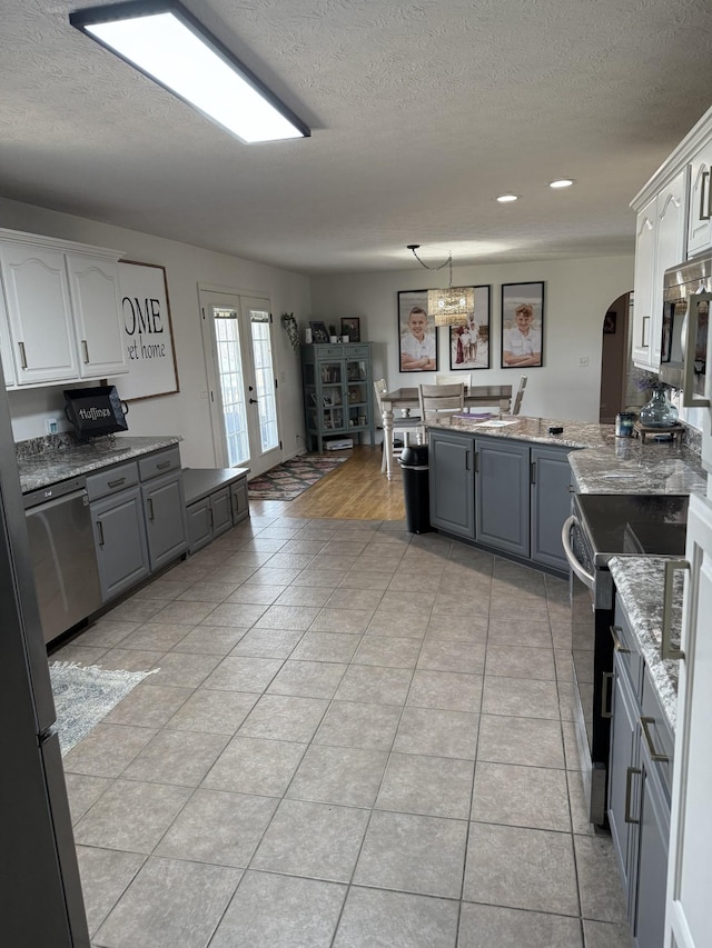 273 Old Coleytown Ln, Lafayette, TN 37083 - kitchen featuring gray cabinetry, a textured ceiling, stainless steel appliances, a peninsula, and light stone counters