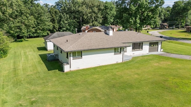 215 Sunset Dr, New Johnsonville, TN 37134 - back of property with asphalt driveway, a garage, roof with shingles, and a lawn