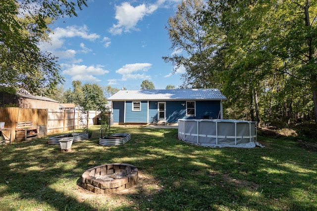 614 Joshua Dr, Clarksville, TN 37042 - back of property featuring a fire pit, an outdoor pool, a vegetable garden, and a metal roof